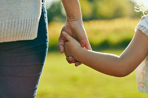 Adult and child holding hands, symbolizing love, trust, and protection