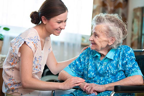 Caregiver and elderly patient smiling and having a conversation