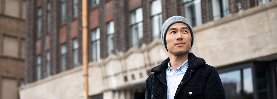 Young Asian man walking through a city, observing his surroundings