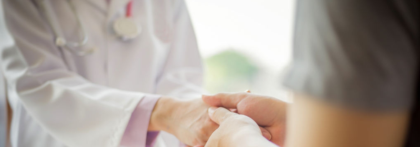 Healthcare provider holding patient's hands in comfort